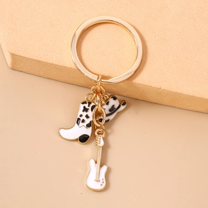 Detailed view of golden keychain featuring cow print cowboy boot, hat and guitar charms