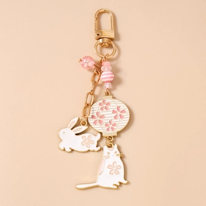 Detail of cherry blossom charms including a cat, rabbit, and lantern on a golden keychain