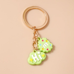 Detail of light green cloud and round letter pendant on golden metal keychain hook
