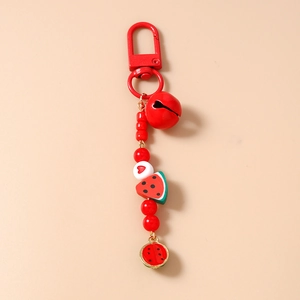 Detail view of handmade beaded watermelon keychain with red bell and heart bead charm