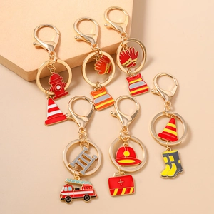Golden firefighter theme keychain set featuring fire truck and helmet charms on beige surface