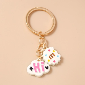 Close-up of golden keychain featuring cute cloud pendant and lettered biscuit charm