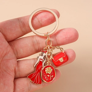 Détail d'un porte-clés doré avec femme en robe rouge, sac à main et médaille Love