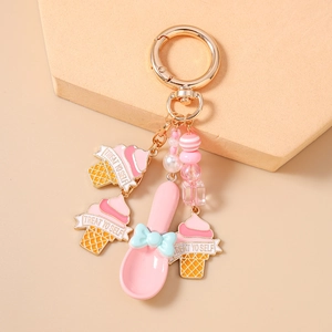 Detail of pink ice cream cone pendants and spoon on a golden metal keychain