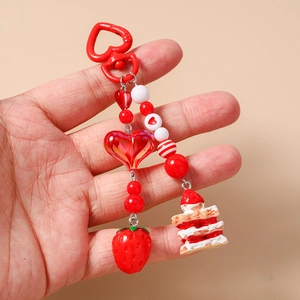 Detail of red strawberry cake keychain with beaded heart charms for bag accessory