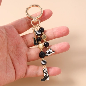 Close-up of golden guitar and cowboy boot charms on a beaded keychain pendant