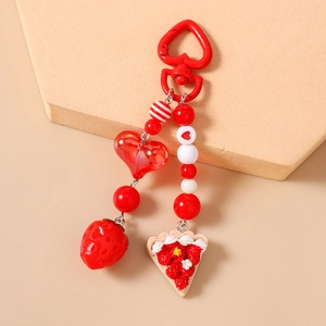 Detail view of strawberry cake keychain with red heart clasp and beaded charm details