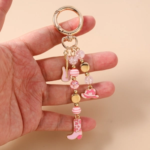 Detailed view of pink guitar and cowboy hat charms on a golden metal keychain link