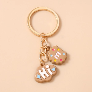 Detail view of cartoon cookie and cloud resin pendants on a gold keychain ring