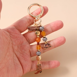 Detail of beaded cowboy keychain with golden spring clasp and western hat boots charms