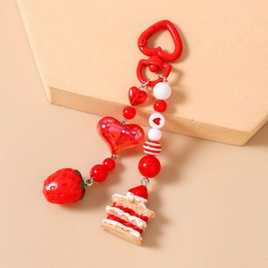 Detail of beaded keychain with artificial strawberry cake and red heart charms