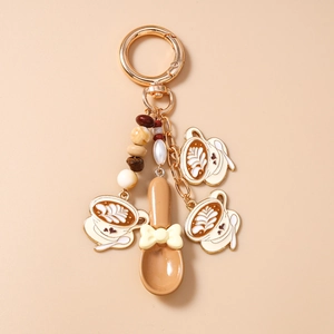 Detail of coffee theme keychain featuring enamel latte cups and beaded charms with golden spoon