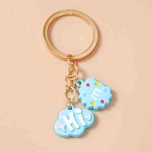 Detail of light blue cloud and letter m cookie charms on a golden keychain