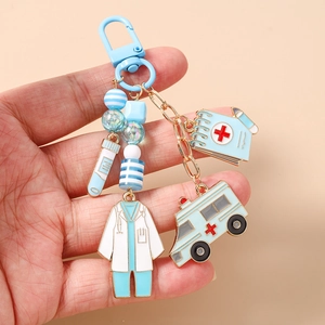 Dettaglio portachiavi a tema medico con ciondoli ambulanza e camice da dottore