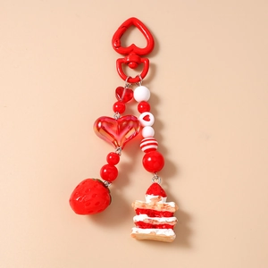 Close-up of strawberry cake keychain with beaded heart charms and red metal clip