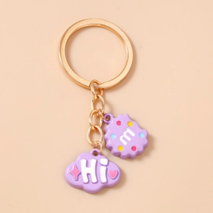 Close-up of cute purple cartoon charms with cloud and m-letter biscuit on golden keychain