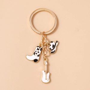 Detail of cow print cowboy boot, hat, and guitar charms on a golden keychain
