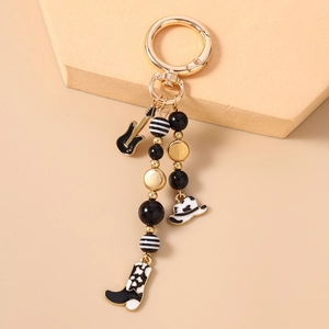 Close-up of guitar and cowboy boot charms with beads on a gold keychain hook