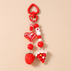 Close-up of strawberry cake keychain with red heart clasp and beaded charms