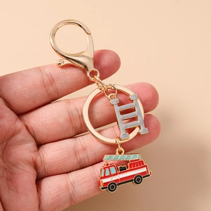 Detailed close-up of golden firefighter keychain with red fire truck and ladder charms
