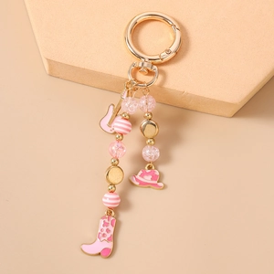 Pink and gold beaded keychain with enamel guitar, cowboy hat, and boot charms
