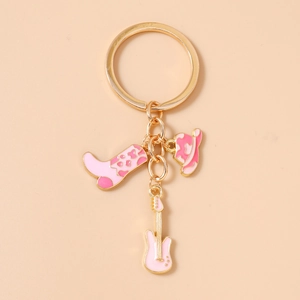 Detail of gold keychain with pink enamel cowboy hat, boot, and electric guitar charms