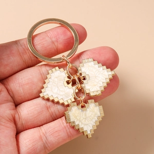 Close-up of golden mosaic pixel heart charms keychain with cream enamel inlay details