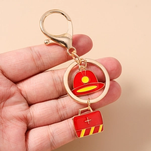 Detail of firefighter keychain with red helmet and medical box enamel pendants
