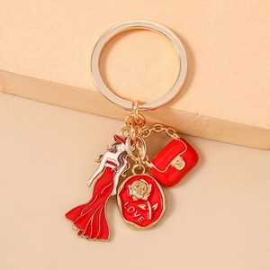 Détail du porte-clés doré avec charms en émail rouge représentant une dame et un sac