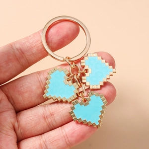 Detail of pixel art heart keychains in sky blue with gold metallic ring and accents