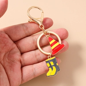 Detail of firefighter keychain with traffic cone and boot charms in golden finish