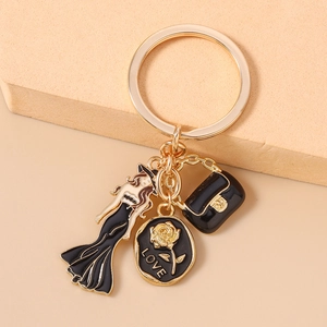 Détail du porte-clés doré avec figurine de femme, pendentif rose love et mini sac noir