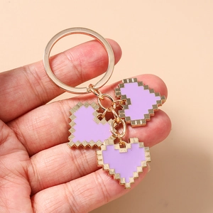 Detail of lavender pixel heart keychains with gold metal rings held in hand