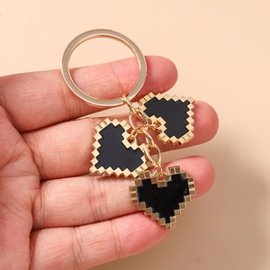 Detail of pixel art heart keychain with golden metal rings and black enamel charms