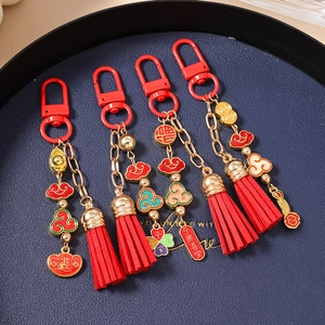 Detailed view of traditional Chinese red tassels and gold ingot charms on bag pendants