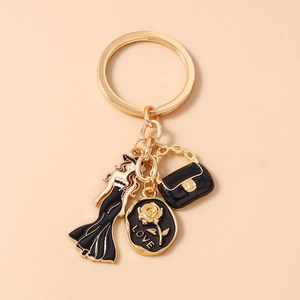 Détail d'un porte-clés doré avec figurine de femme, sac à main et disque gravé de rose