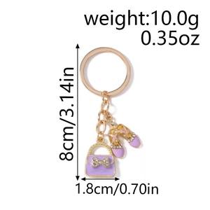 Detailed view of purple enamel handbag and ballet shoes charms on a gold keychain