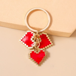 Detailed close-up of golden keychain with three red mosaic pixel heart pendants