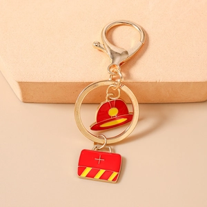 Detail of firefighter helmet and medical bag pendants on a gold keychain clasp