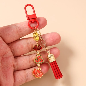 Close-up of red tassel and traditional Chinese golden ingot charm on keychain