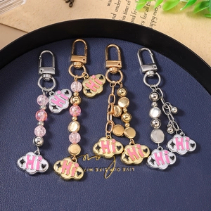 Close-up of beaded cloud keychain charms with Hi engraving on premium leather tray