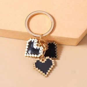 Detail of pixel art heart charms on a golden metal keychain with 8-bit aesthetic style