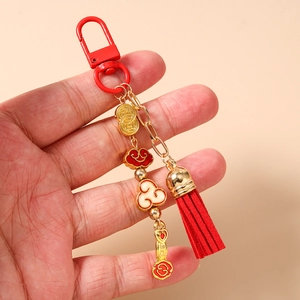 Close-up of Chinese auspicious key chain with gold ingot, enamel cloud and red leather tassel