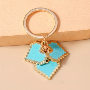 Detail of pixel heart keychain with gold rings on a textured display stand