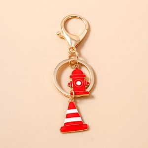 Close-up of golden metal keychain with red fire hydrant and traffic cone enamel charms