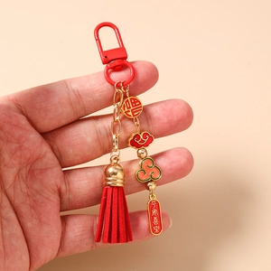Close-up of red tassel keychain with gold blessing charms and Chinese lucky symbols