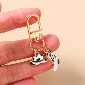 Détail du porte-clés cowboy avec bottes et chapeau à motif vache noir et blanc