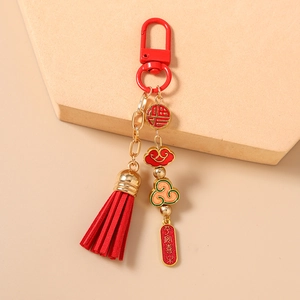 Detail of Chinese style keychain with red tassel, gold fortune charms and cloud motif