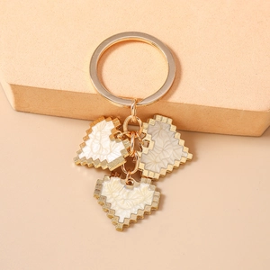 Macro detail of pixelated heart charms on a gold keychain with fine embossed patterns