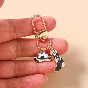 Détail du porte-clés doré avec breloques émaillées chapeau et botte à motif vache
